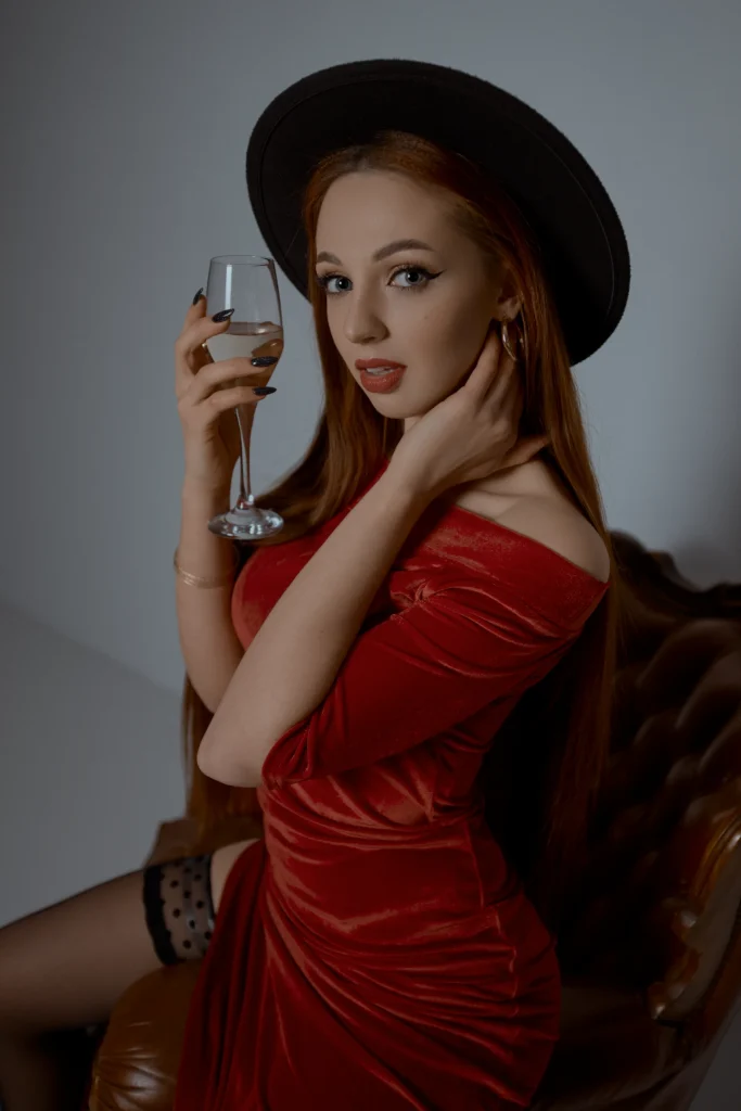дівчина у червоному платті в капелюсі з шампанським